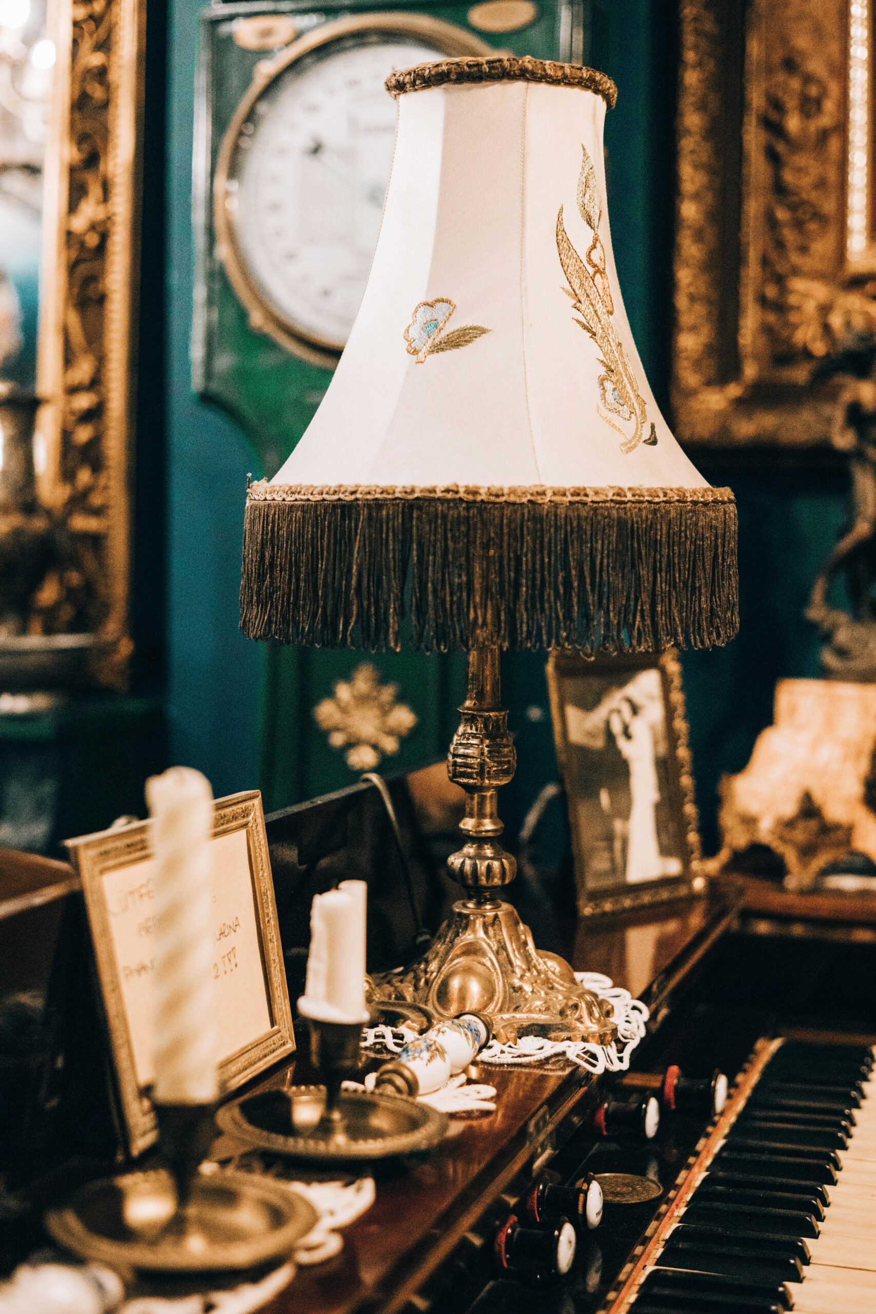 A vintage table lamp sits elegantly on an antique piano in a classic room filled with ornate decor.